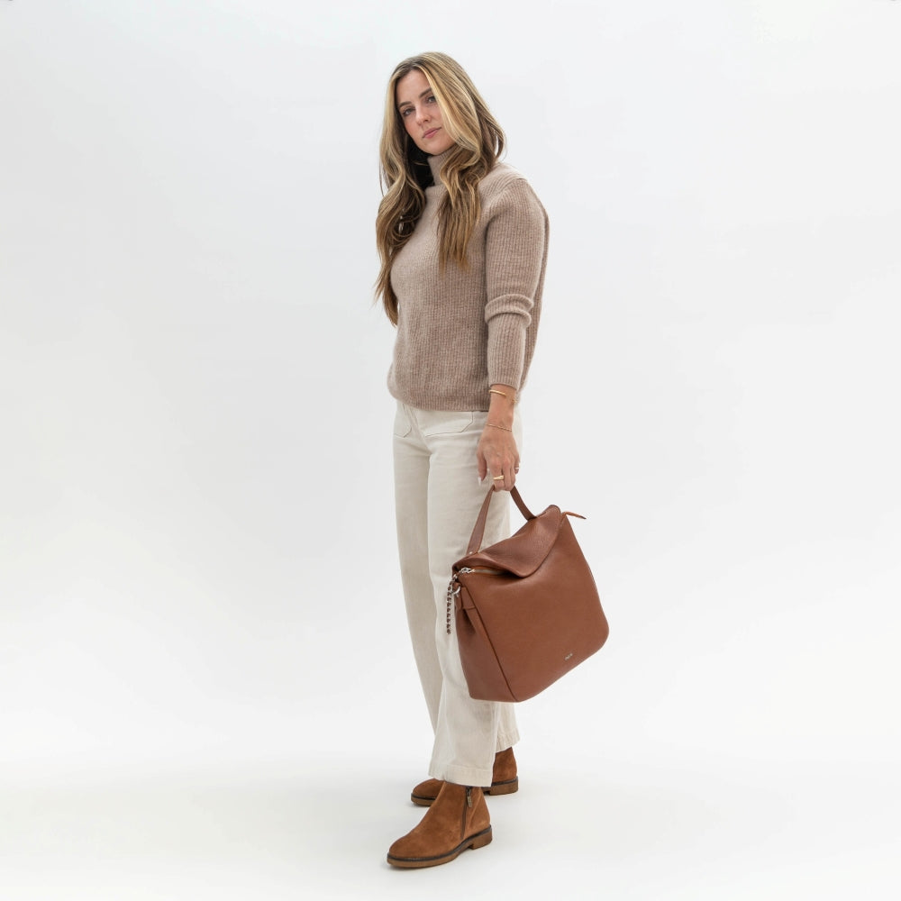 Woman holding a brown leather bag against a white background