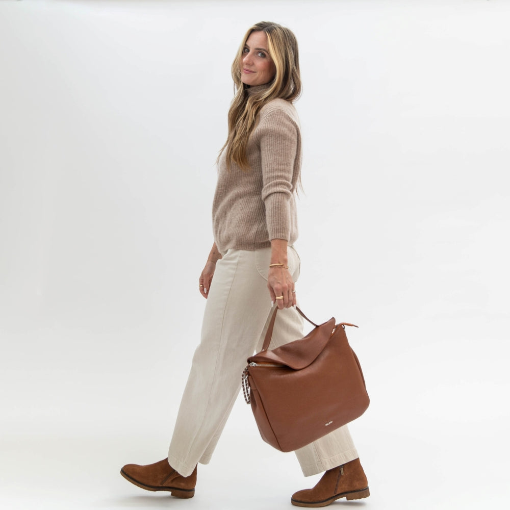 Woman holding a brown leather bag against a white background