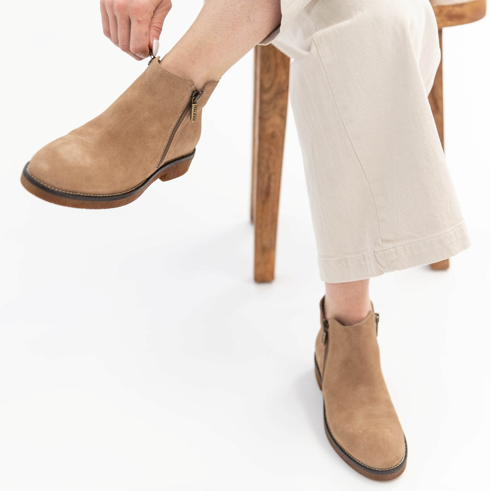 Person wearing brown ankle boots on a white background