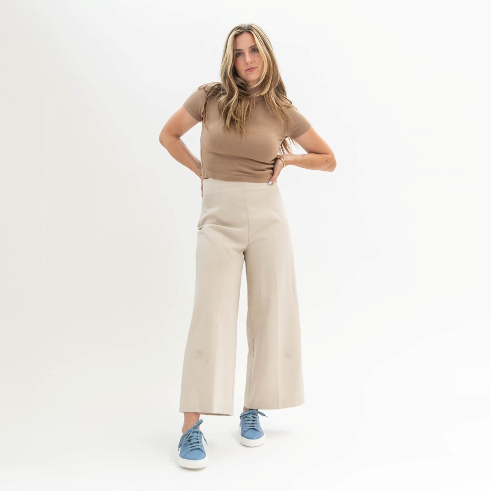 Woman wearing a brown top and beige wide-leg pants on a white background